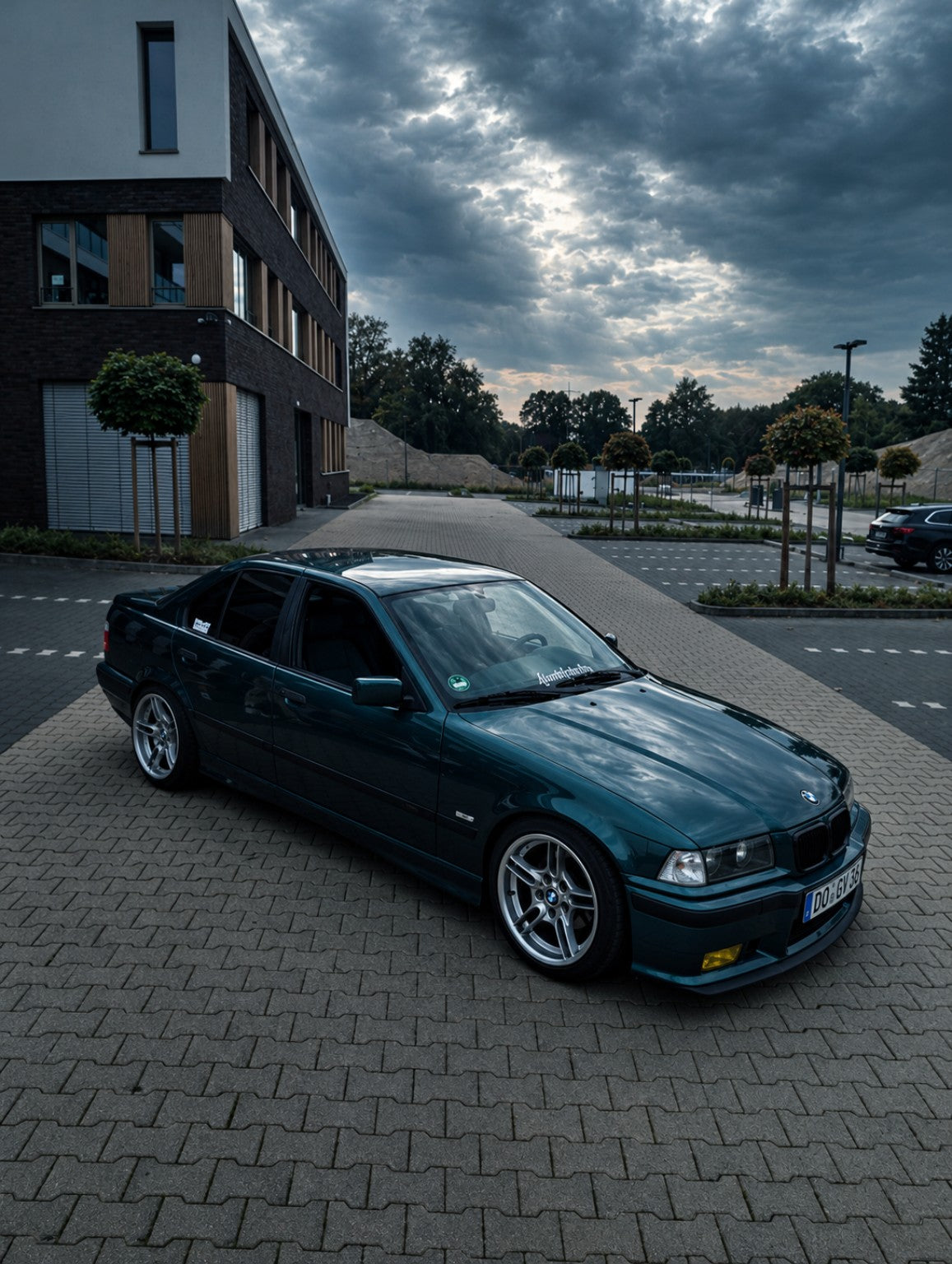 Dunkelgrüner BMW mit Armageddon Club Sticker bei bewölktem Himmel